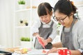 Asian Kid and young mother decorating cookies. Royalty Free Stock Photo