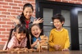 Asian Kids and their teacher are playing wooden blocks stack gam