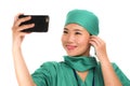 Asian Korean woman as successful taking selfie on hand phone - young beautiful and happy medicine doctor or hospital nurse taking Royalty Free Stock Photo