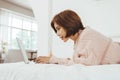 Asian Korean woman lying on the bed using laptop Royalty Free Stock Photo