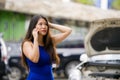 Asian Korean woman in stress stranded on street suffering car engine failure having mechanic problem calling on mobile phone for Royalty Free Stock Photo