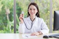 Asian lady doctor wears medical coat and stethoscope and shows its in office room at hospital in health check concept Royalty Free Stock Photo