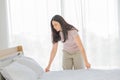 Asian lady making bed in her morning routine after wake up for tidying up the bedroom