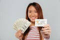 Asian lady over grey wall holding money and credit card. Royalty Free Stock Photo