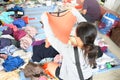 An asian lady picking up a piece of clothing at a free market