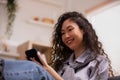 Asian lady sits on sofa at home, texting and talking with buddy, holding smartphone, shopping online, or checking mobile app or Royalty Free Stock Photo