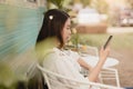 Asian lady sitting outdoor relax looking at smartphone feel leisure in holiday