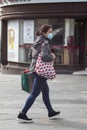 Asian lady walking in the street wearing a face mask with shopping bags