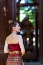 Asian lady wear a traditional costume standing in the classic thai house.The beautiful girl in folk costume is happily at the Thai