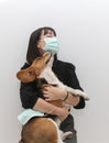 Asian lady wearing protective face mask giving big hug to a cute beagle dog