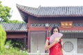 Asian lady wearing red cheongsam in garden, holding a pink color fan in her hand Royalty Free Stock Photo