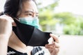 Asian lady woman is wearing a second mask,people putting double or a medical protective mask under a cloth mask for COVID-19