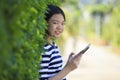 Asian leaning green leaves with computer tablet in hand smiling