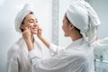 Asian lesbian gay couple putting smooth and skin care for facial soft. Attractive funny woman friend touches on face and apply Royalty Free Stock Photo