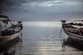 Asian lifestyle landscape traditional asian boats directed towards the horizon in calm sea during dark moody sunset