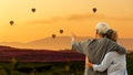 Asian Lifestyle senior couple hug and pointing balloon on mountain with field cosmos in sunrise nature.  Old people happy in love Royalty Free Stock Photo