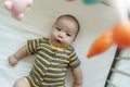 Asian little baby boy lying on bed having fun playing with colorful mobile hanging