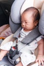 Asian little baby fastened with security belt in safety car seat Royalty Free Stock Photo