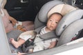 Asian little baby fastened with security belt in safety car seat Royalty Free Stock Photo