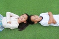 Asian little boy and girl child lying on green grass background together with looking camera Royalty Free Stock Photo