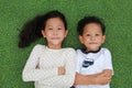 Asian little boy and girl child lying on green grass background together with looking camera. Above view Royalty Free Stock Photo