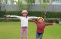 Asian little boy and girl child wearing straw hat standing and open wide arms with looking camera in the garden Royalty Free Stock Photo