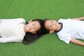 Asian little boy looking camera and girl kid closed eyes lying on green grass background. Above view Royalty Free Stock Photo