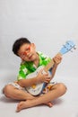 Asian little boy playing ukulele Royalty Free Stock Photo