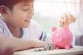 Asian Little boy saving money in pink piggy bank. Royalty Free Stock Photo