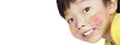The Asian little boy smiled and had a smear of watercolor paint on his face