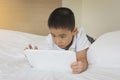 Asian little boy using tablet computer in bed Royalty Free Stock Photo