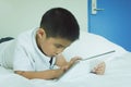 Asian little boy using tablet computer in bed Royalty Free Stock Photo