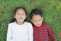 Asian little child boy and girl lying on green grass outdoors in summer park. Portrait of sister and brother resting in garden Royalty Free Stock Photo