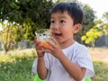 Asian little child boy holding glass of orange juice with smiling happy face Royalty Free Stock Photo