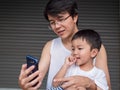 Asian little child boy watching smart phone with dad.