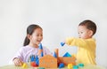 Asian little child girl and baby boy playing a colorful wood block toy on table over white background. Sister and her brother Royalty Free Stock Photo