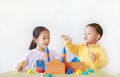 Asian little child girl and baby boy playing a colorful wood block toy on table over white background. Sister and her brother Royalty Free Stock Photo