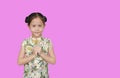 Asian little child girl in chinese traditional dress greeting gesture celebrating for happy Chinese New Year isolated over pink Royalty Free Stock Photo