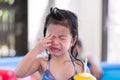 An Asian little child girl is crying while getting wet. Kid cried crying when she was dripping water on her face.