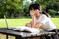 Asian little child girl feeling boring while cramming,studying online,female student with laptop computer and a book on table, Royalty Free Stock Photo