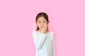 Asian little child girl with finger in nose isolated on pink background. Kid picking at her nostril Royalty Free Stock Photo