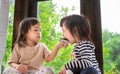 Asian little child girl and her sister are eating banana cupcake in the room deliciously Royalty Free Stock Photo