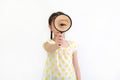 Asian little child girl looking through a magnifying glass isolated on white background. Focus at magnifying glass in hand Royalty Free Stock Photo