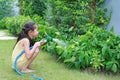 Asian little child girl pouring water spray on trees. Kid watering plants in the garden near his house Royalty Free Stock Photo