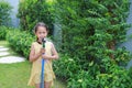 Asian little child girl pouring water spray on trees. Kid watering plants in the garden near his house Royalty Free Stock Photo