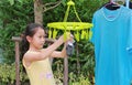 Asian little child girl putting clothespin and hangs socks to dry a clothes. Kid doing laundry in the garden