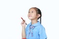 Asian little child girl in school uniform holding Red dipped paintbrush thinking of drawing something over white background Royalty Free Stock Photo