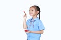 Asian little child girl in school uniform holding Red dipped paintbrush thinking of drawing something over white background Royalty Free Stock Photo