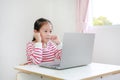 Asian little child girl sitting at desk and using laptop computer Royalty Free Stock Photo