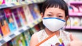 Asian little  child girl wear face mask and  buying school supplies in stationery store.Back to school concept Royalty Free Stock Photo